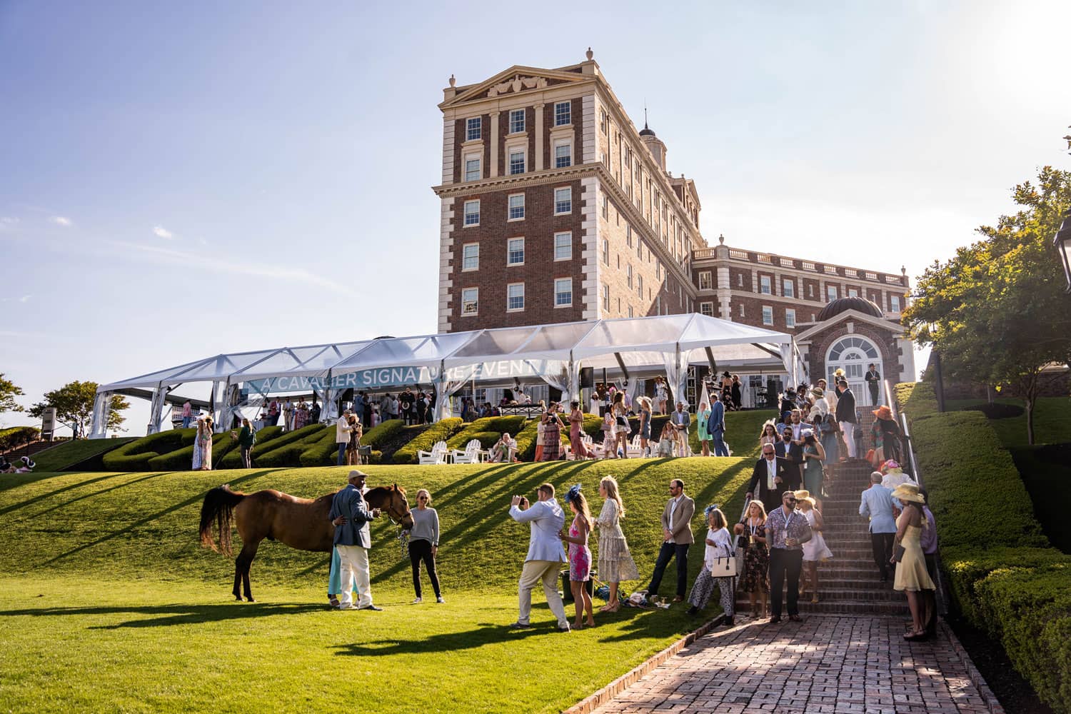 A group posing for a photo with a horse at an event on The Historic Cavalier's Great Lawn