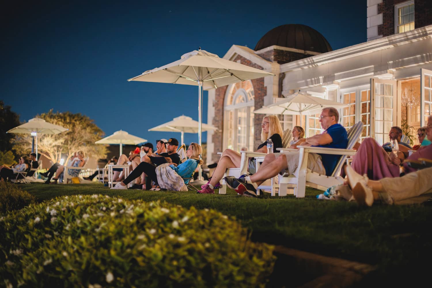 A group of people sitting in lawn chairs watching an outdoor movie.