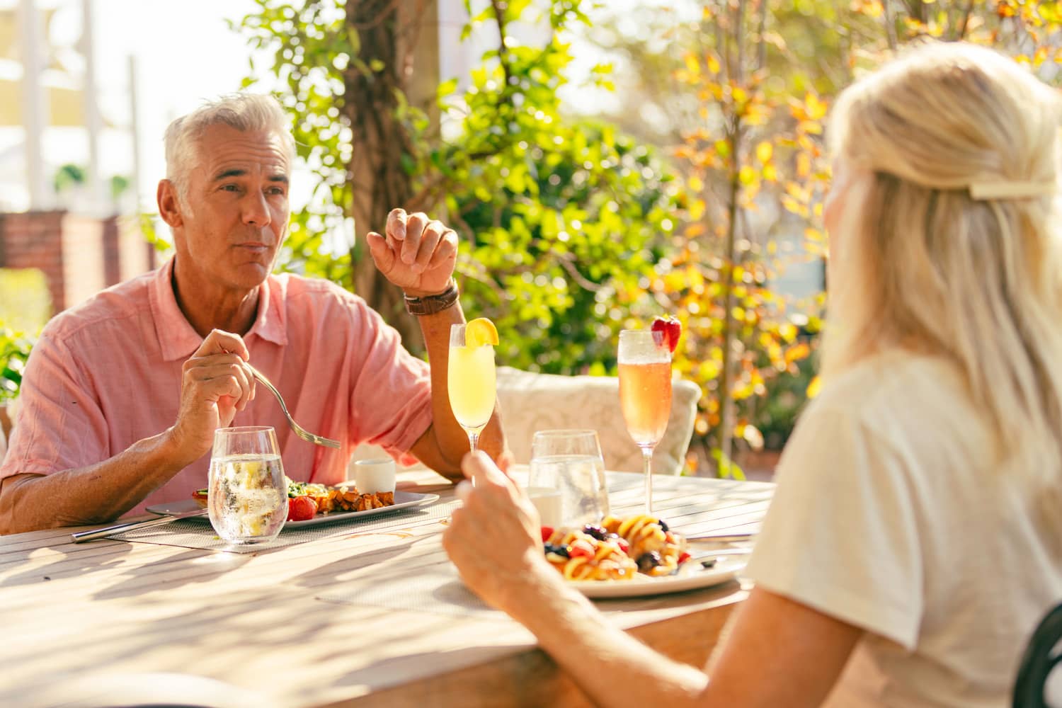 A couple sitting outside eating breakfast together on a sunny day