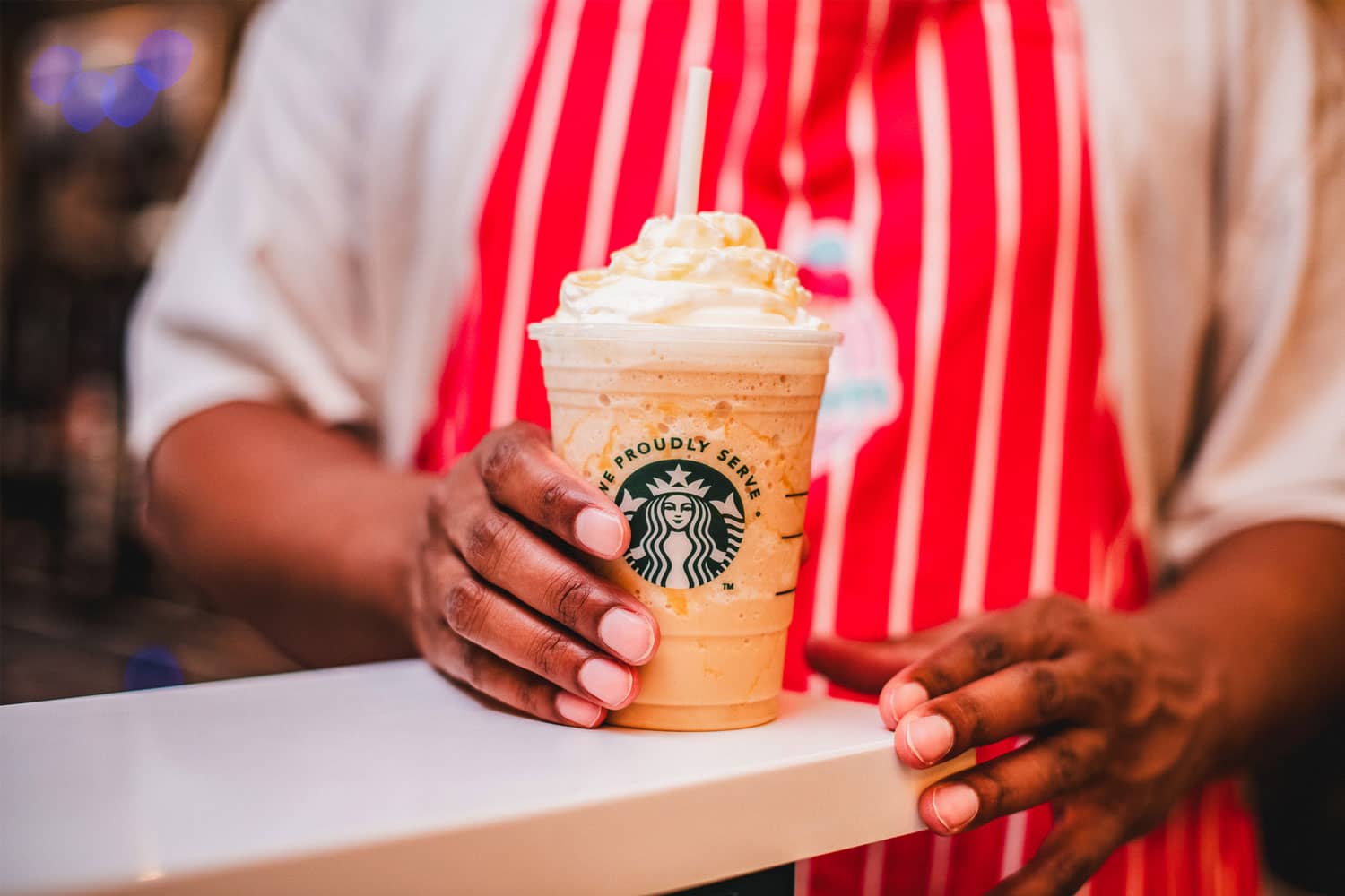 An employee holding a frappe at We Scream Ice Cream & Starbucks