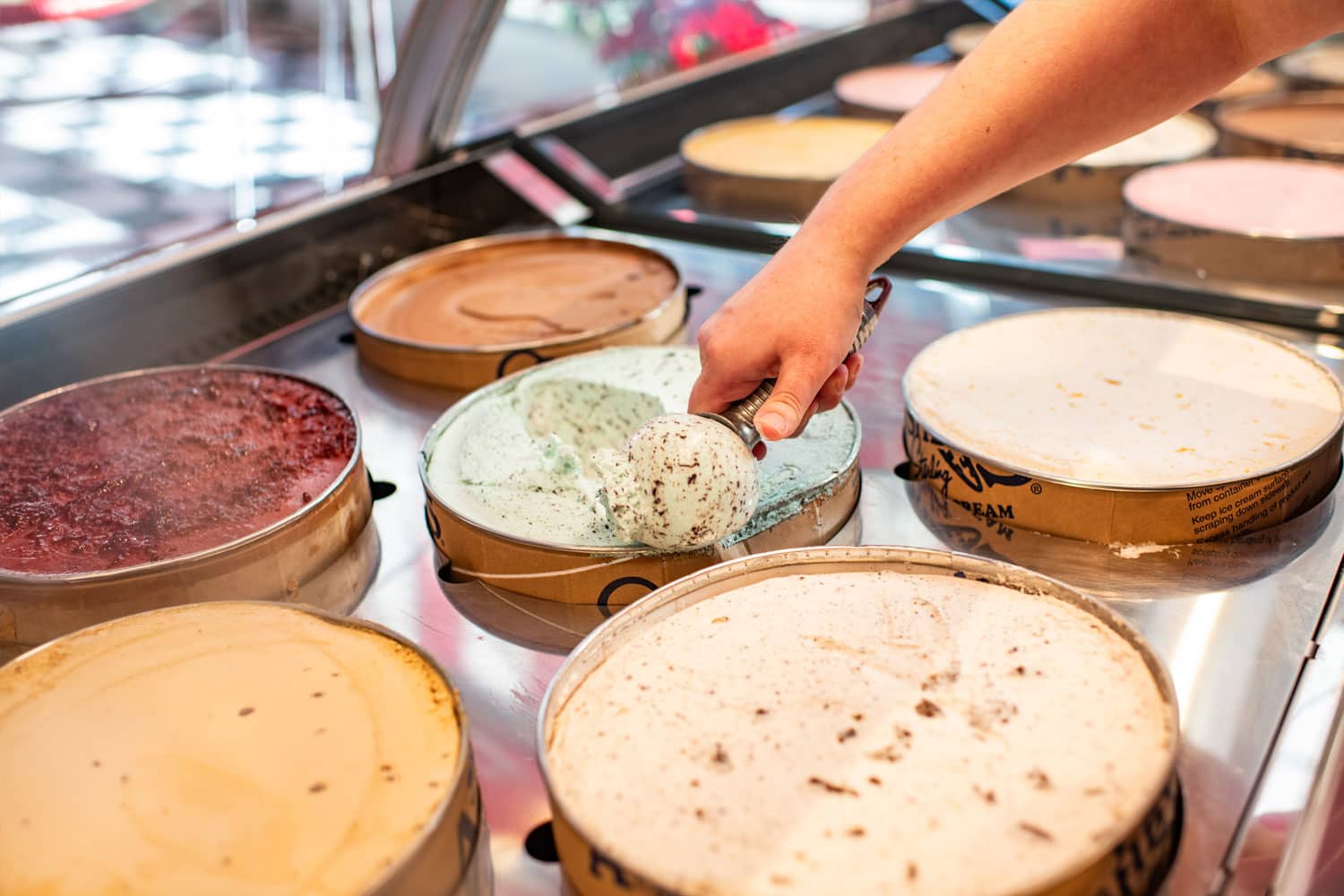An employee scooping ice cream at We Scream Ice Cream & Starbucks