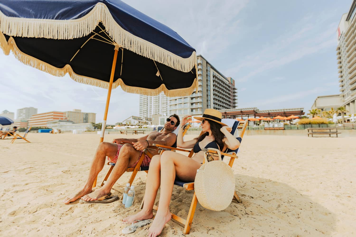A couple sitting in beach chairs under an umbrella at the Cavalier Resort