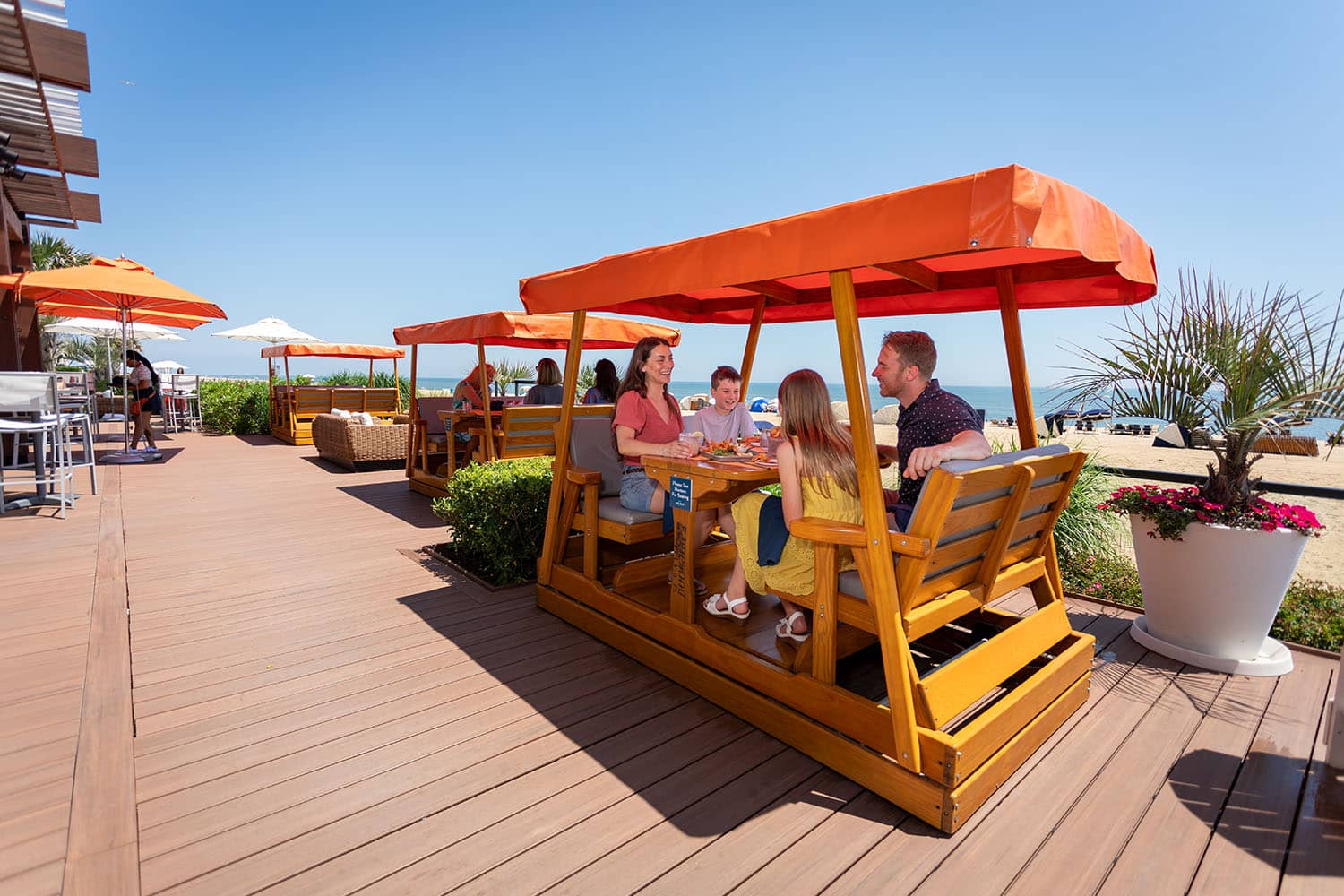 A family sitting outside The Deck Seagrill & Bar eating with oceanfront views