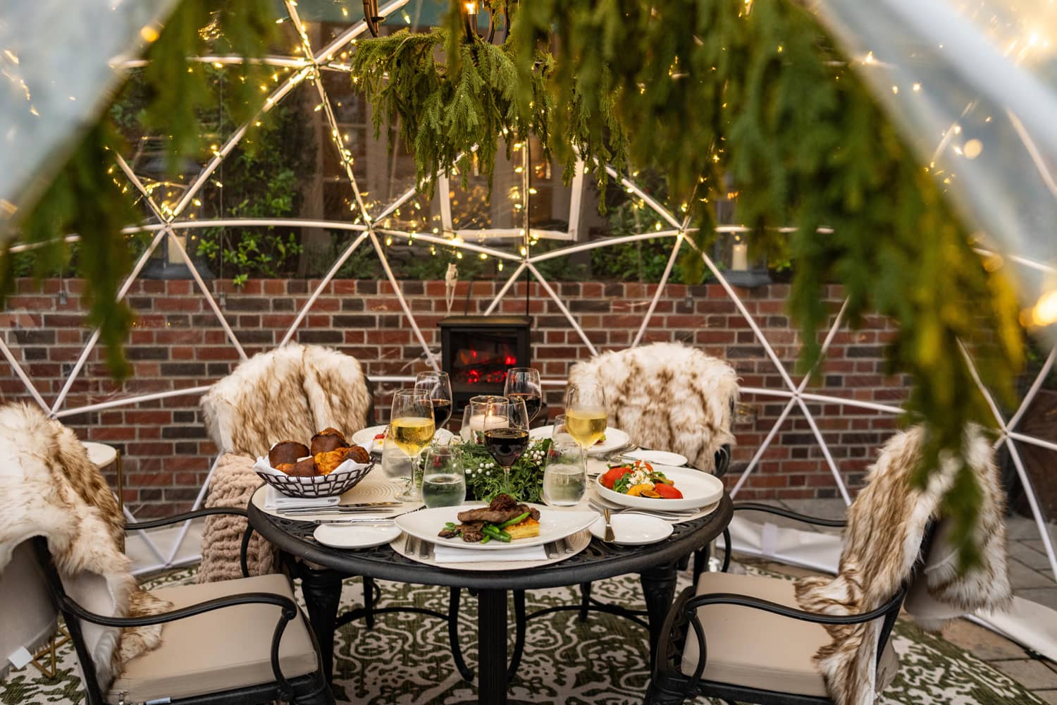A dining table set with food and wine inside a heated igloo