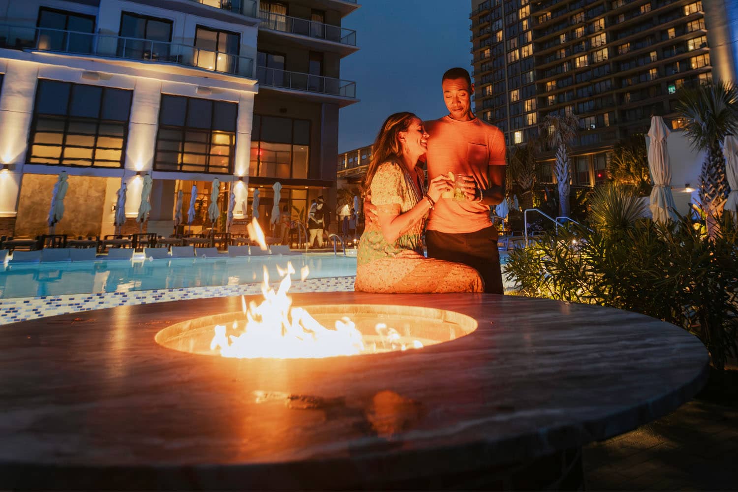 A couple sharing drinks outside next to a firepit