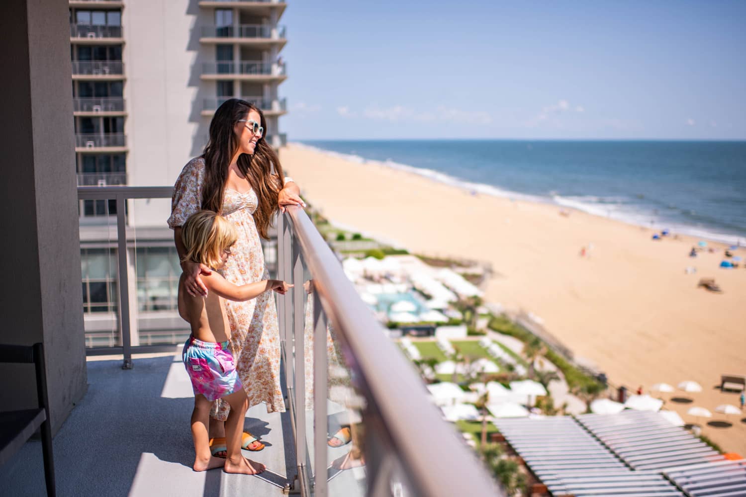 A mom and son on an outdoor balcony suite at the Embassy Suites Virginia Beach Oceanfront Resort