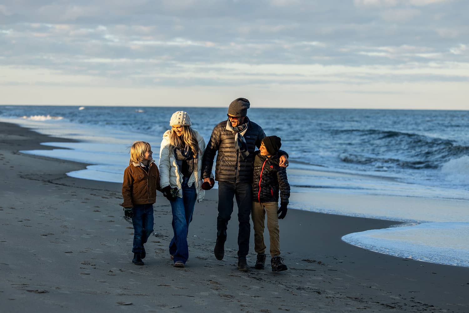 A family walking on a beach during winter