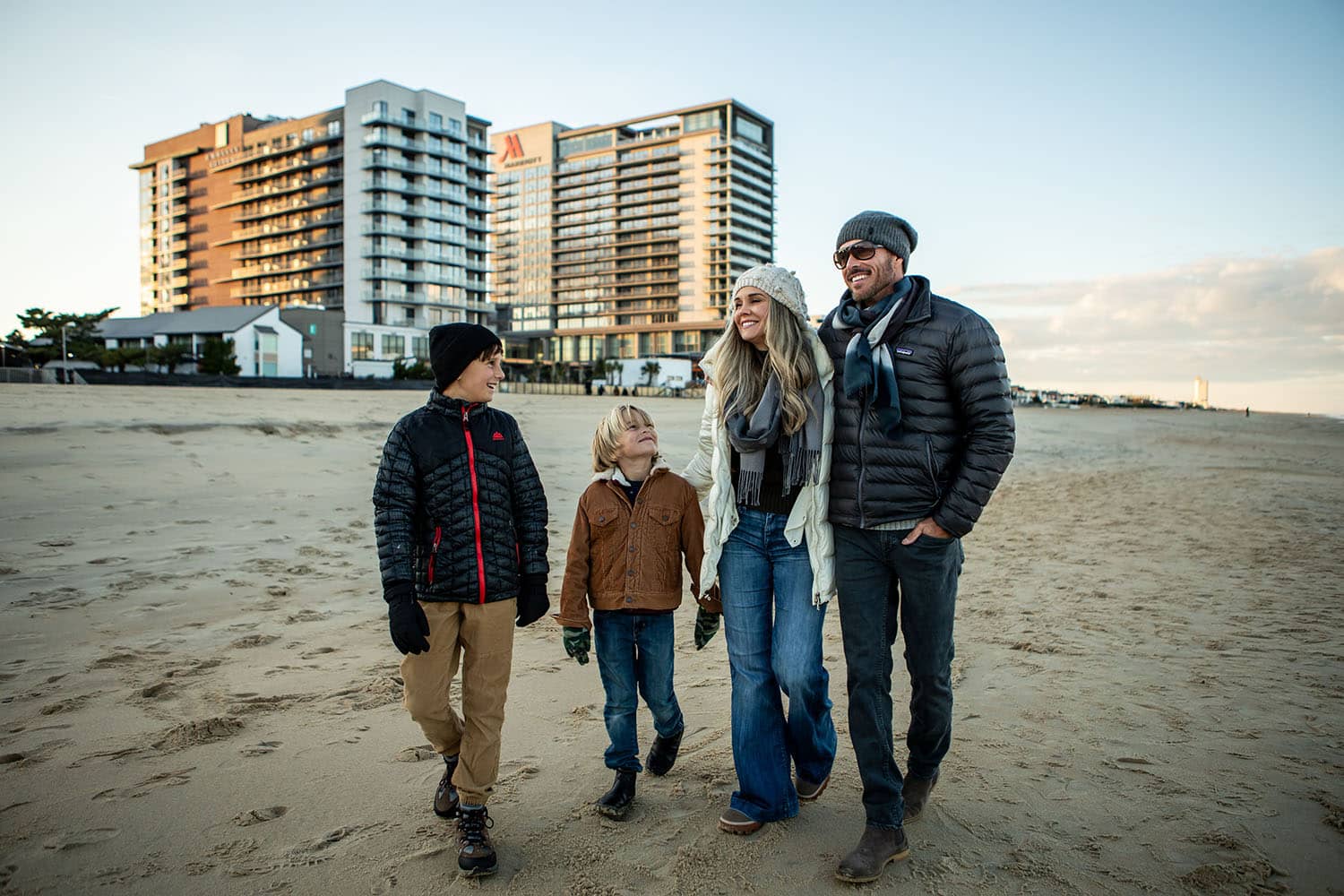 A family walking on the beach outside the Cavalier Resort Virginia Beach