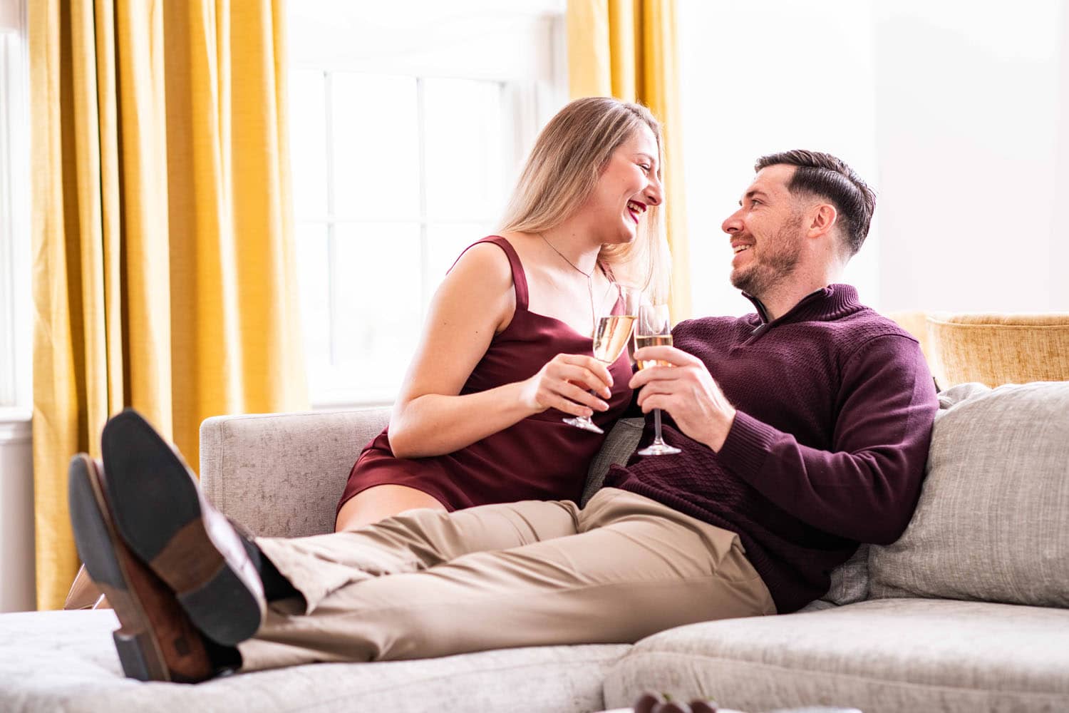 A couple embracing on a couch with champagne