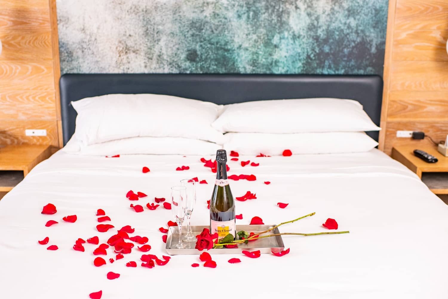 A bed decorated with rose petals and champagne glasses