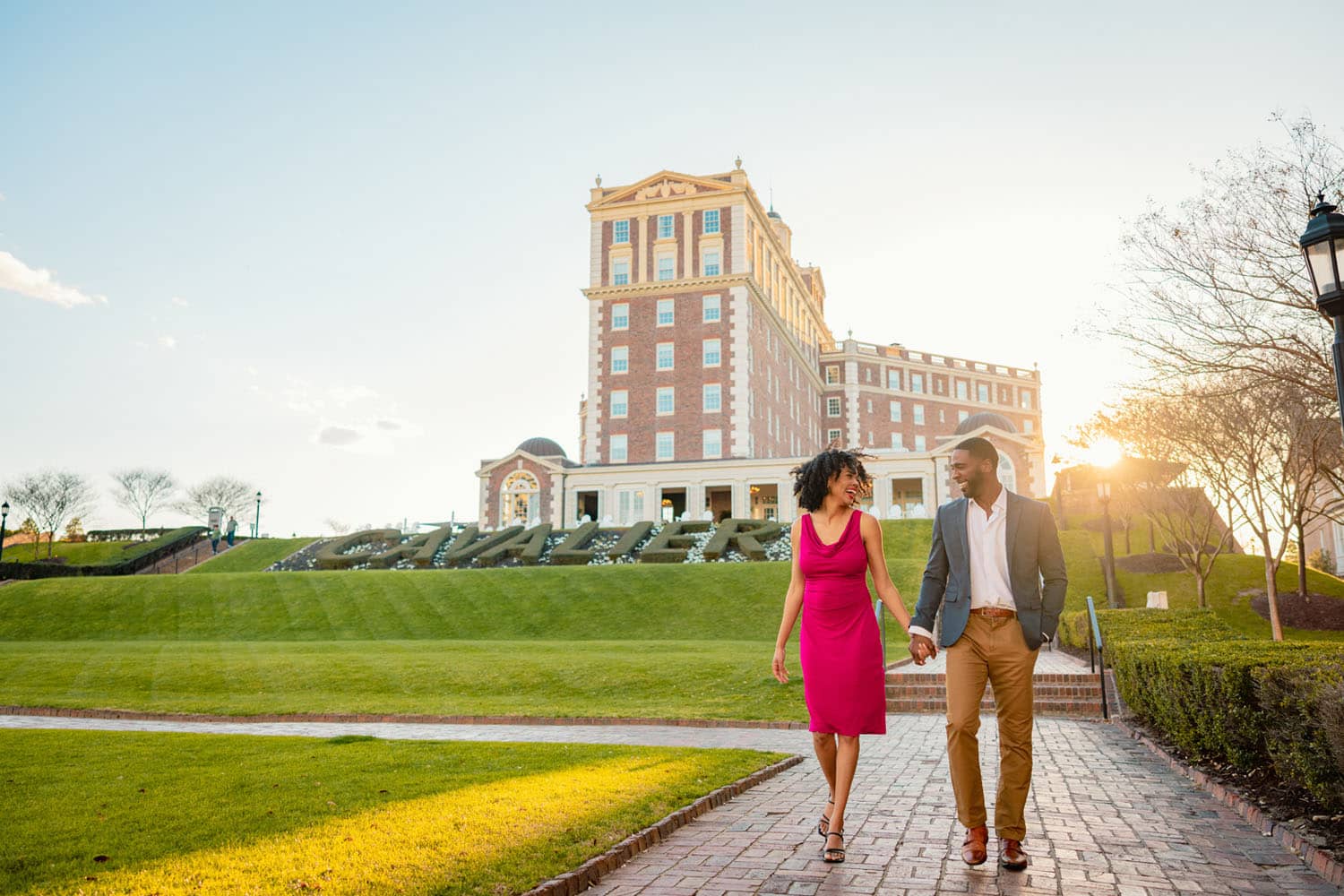 A couple holding hands walking in front of a hotel