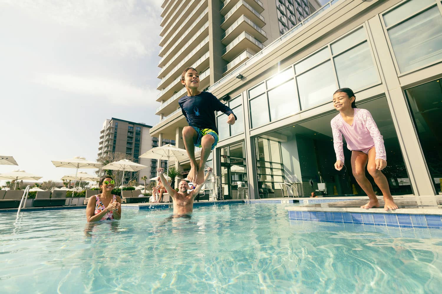 Two children jumping into an outdoor pool