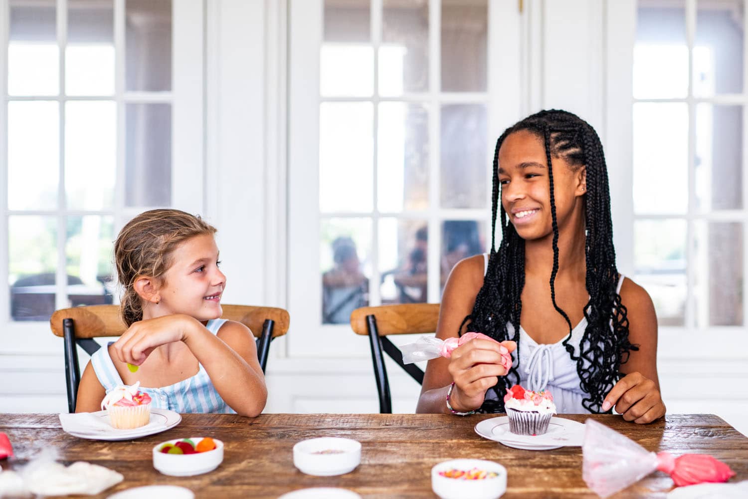 Two children decorating cupcakes at a table