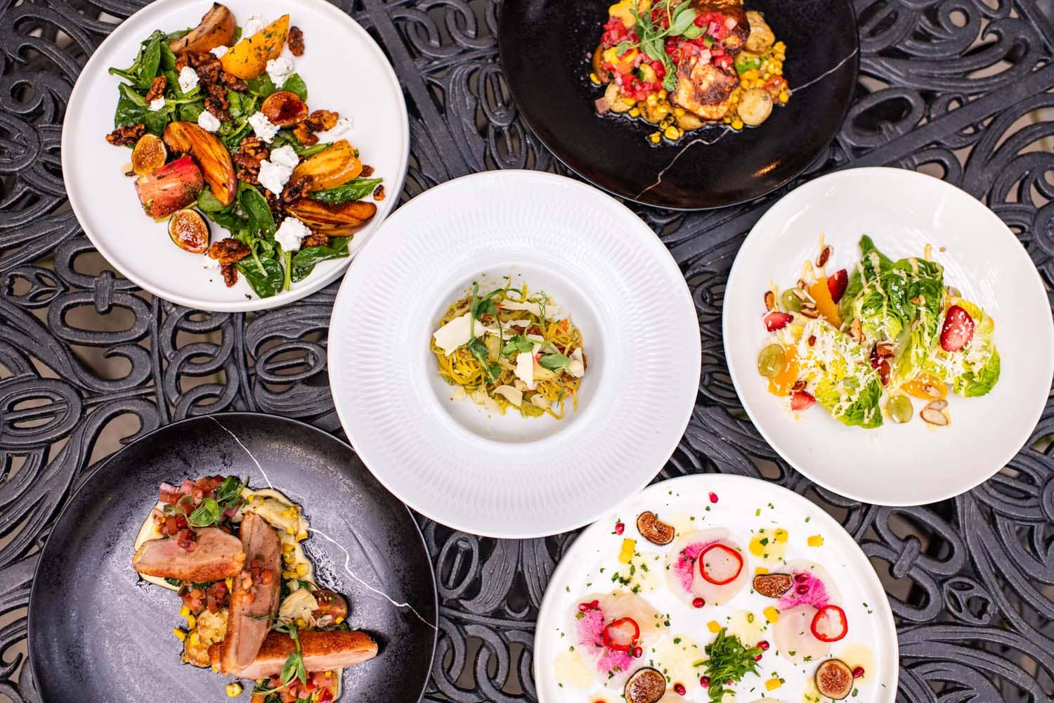 A table with various plated dishes at Becca Restaurant & Garden