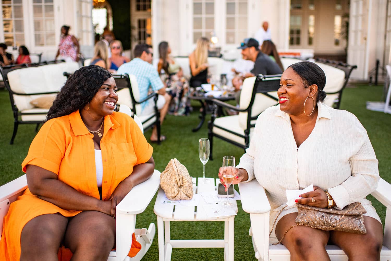 Two women sitting in chairs drinking champagne at dusk