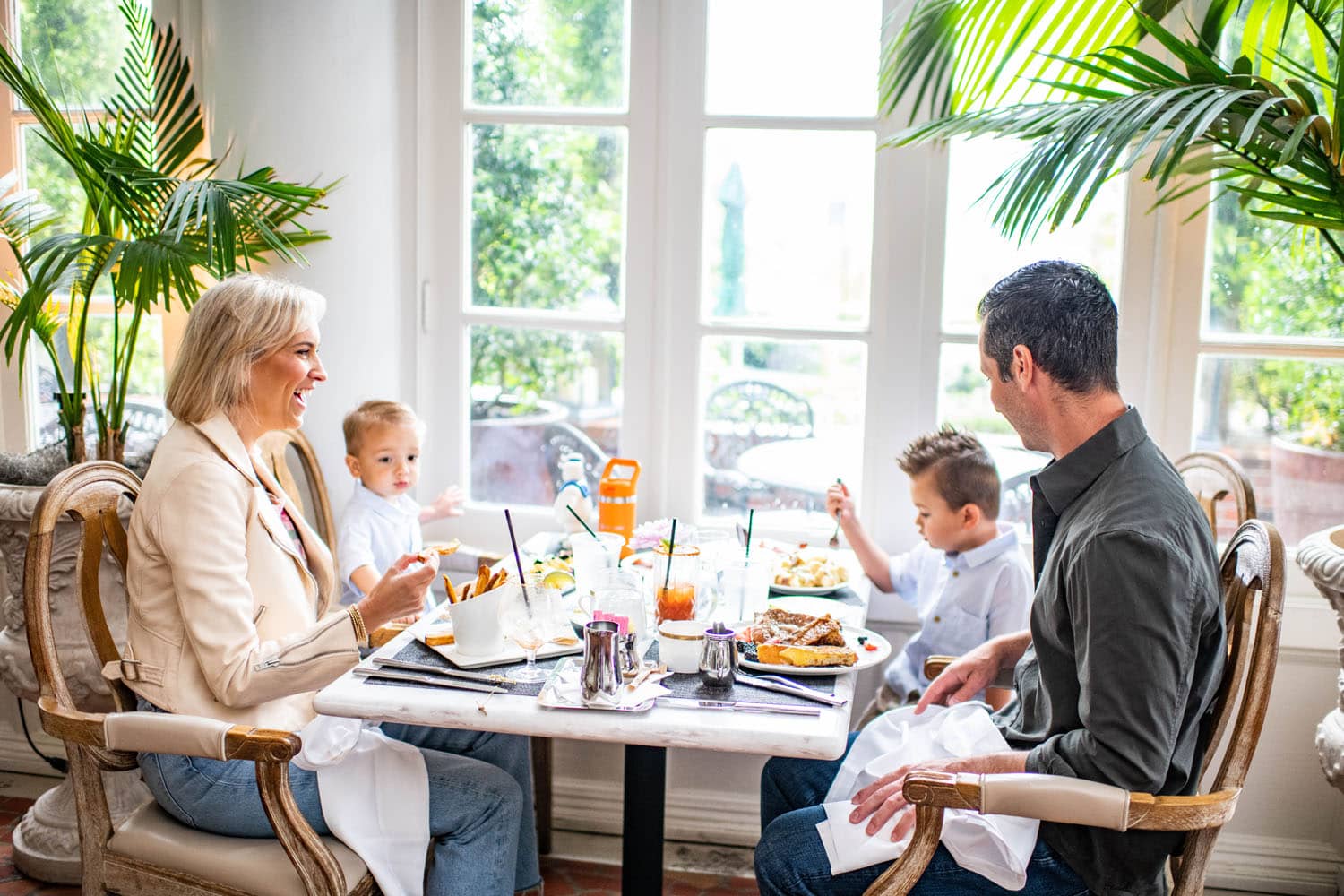 A family enjoying a meal at a table inside Becca Restaurant & Garden