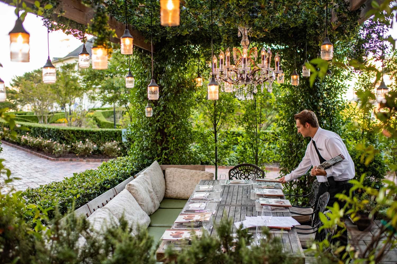 A waiter setting a table outside Becca Restaurant & Garden