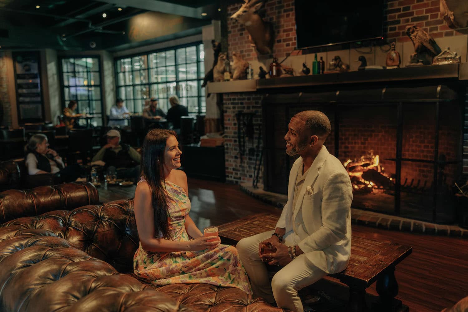 A couple sitting front of a fireplace at the Hunt Room