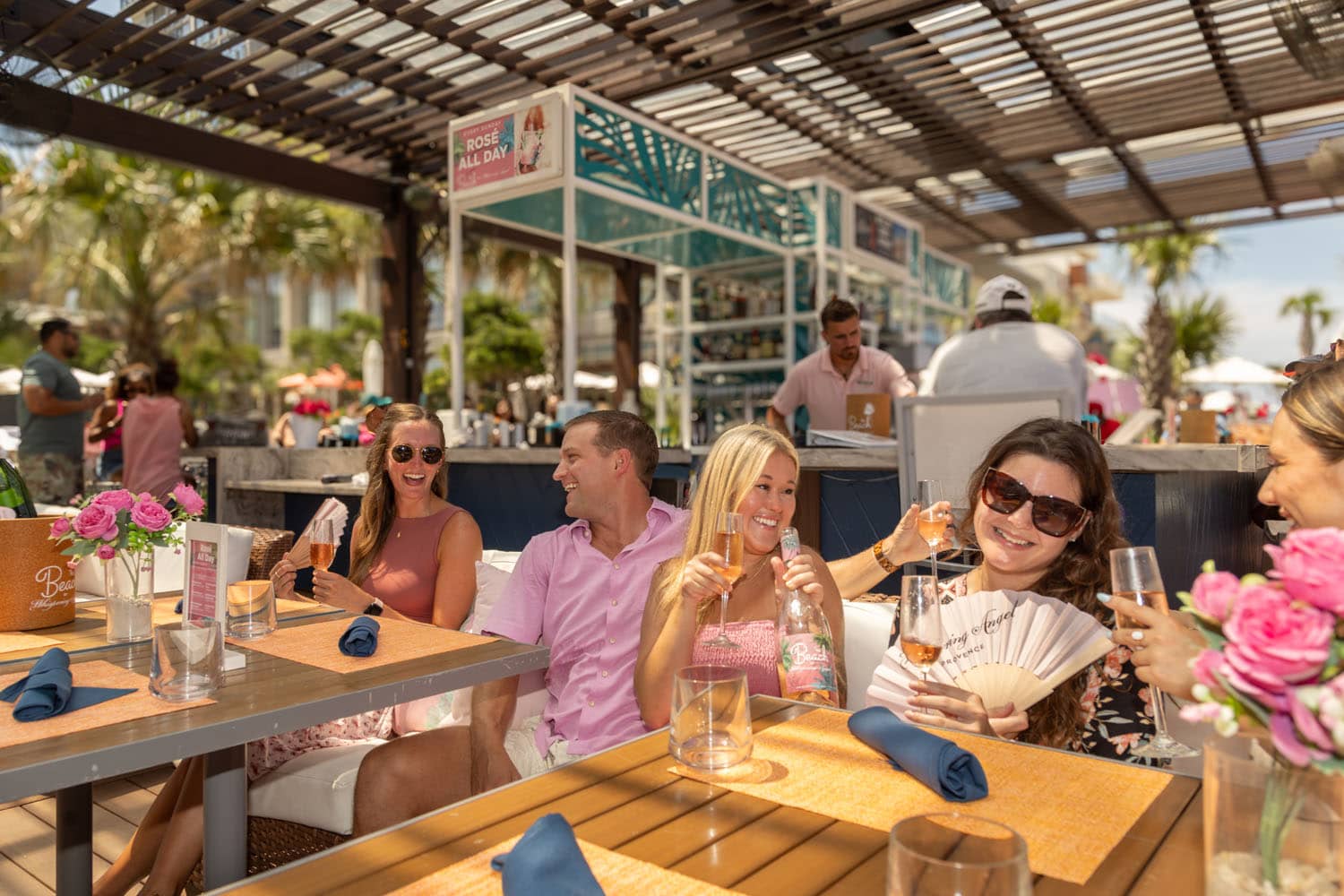 A group of people sitting outside on a deck drinking wine