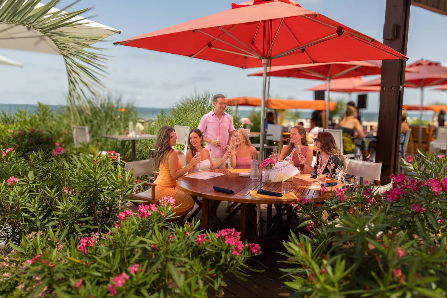 A group of friends sitting outside on a deck under an umbrella