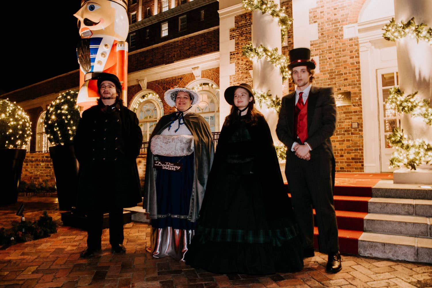 A group of carolers signing songs outside a hotel entrance at night