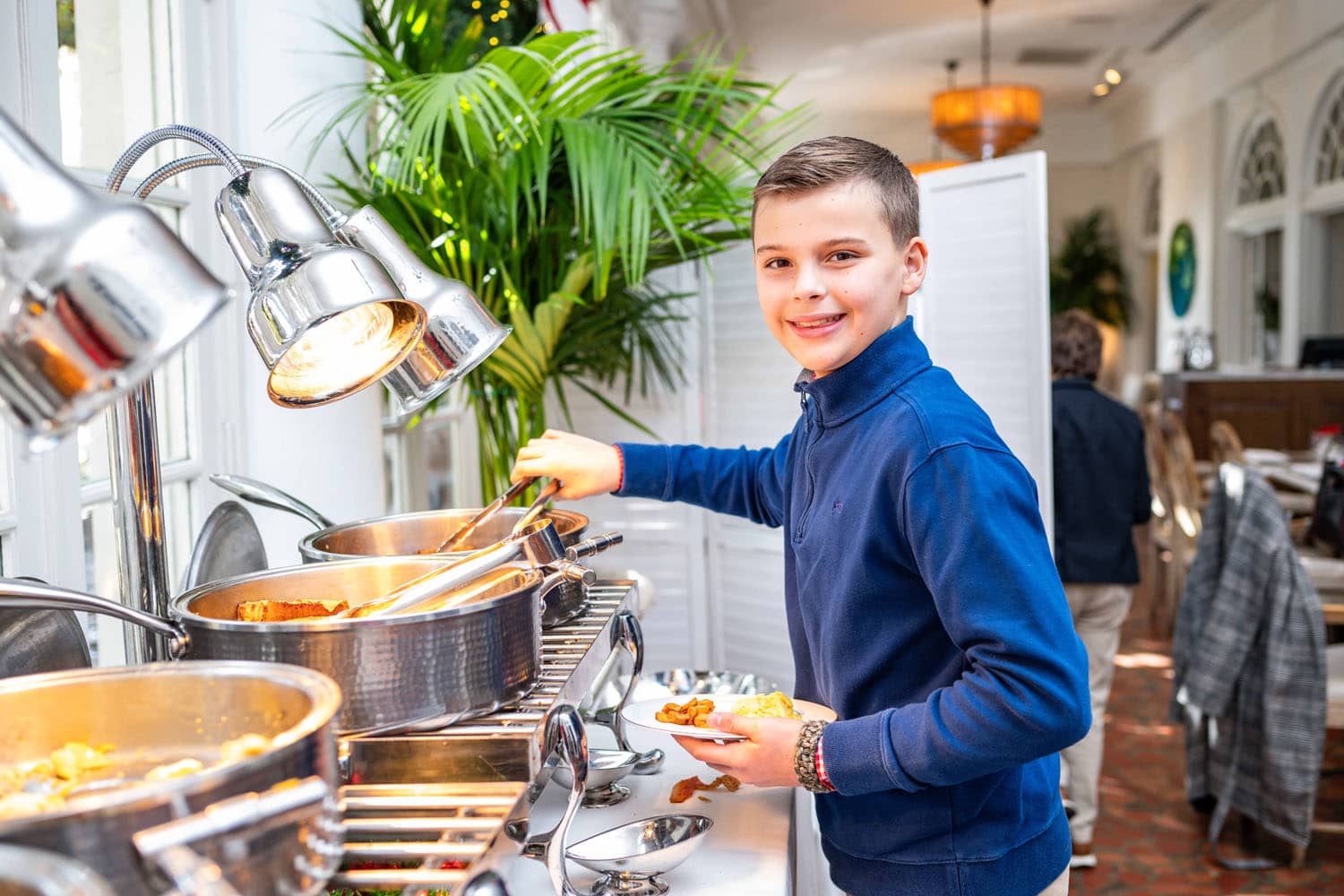 A young child selecting food from a buffet table