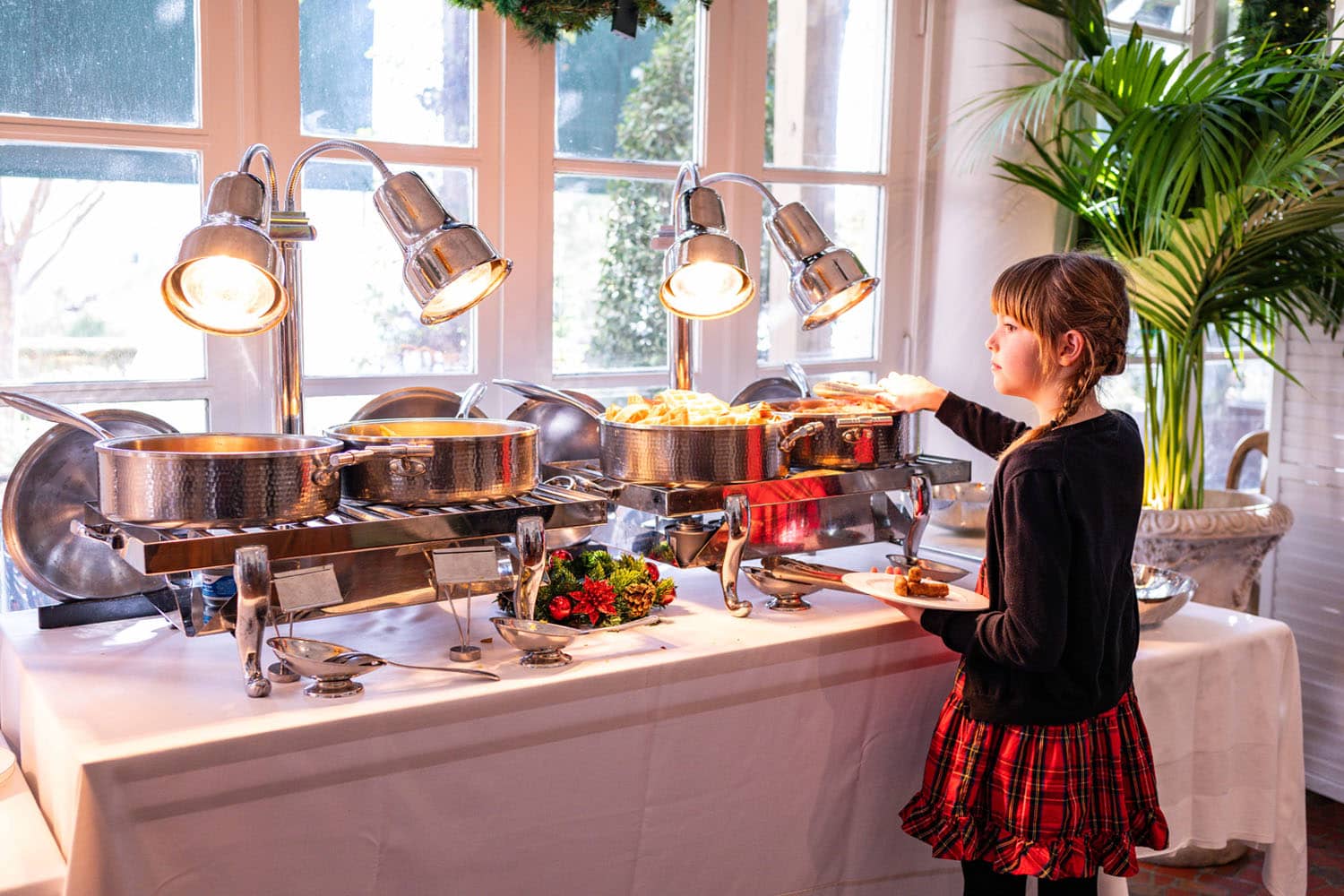 A young child selecting food from a buffet table