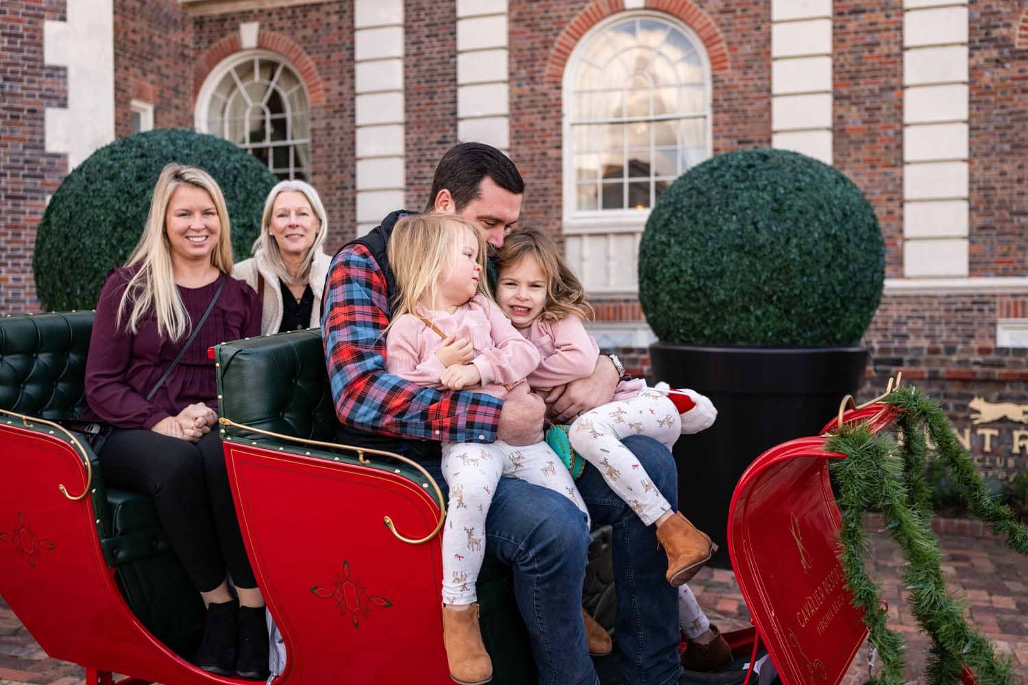 A family sitting a sleigh outside The Historic Cavalier Hotel