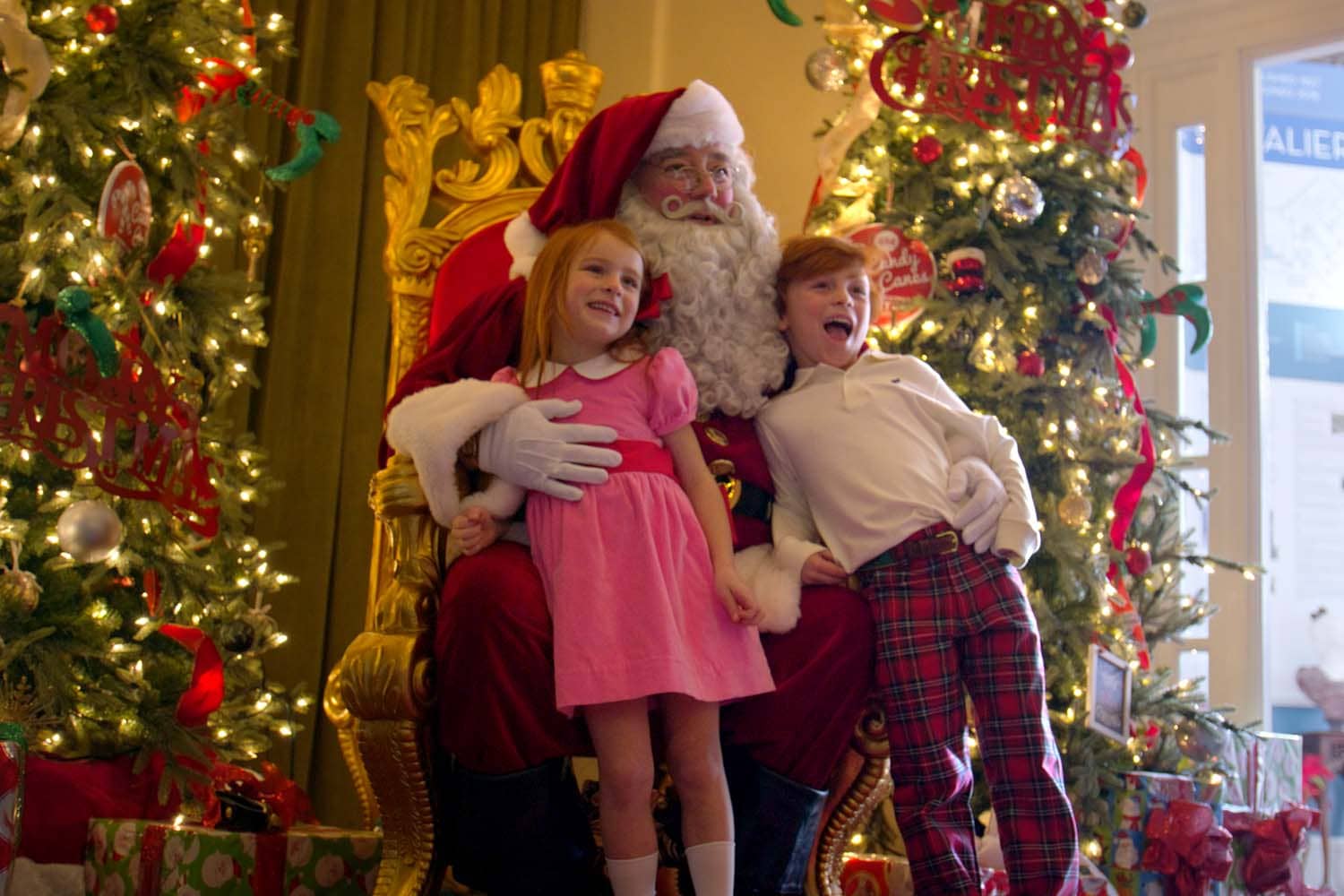 Santa hugging two children at a holiday event