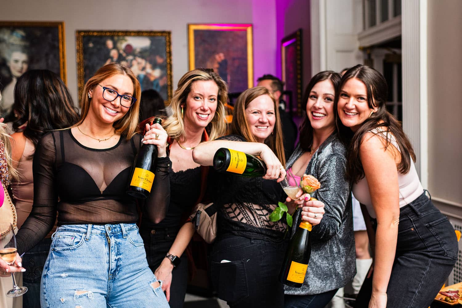 A group of women holding champagne bottles inside a lounge