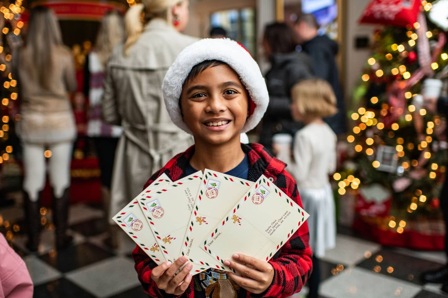 A child holding letters to Santa inside a lobby