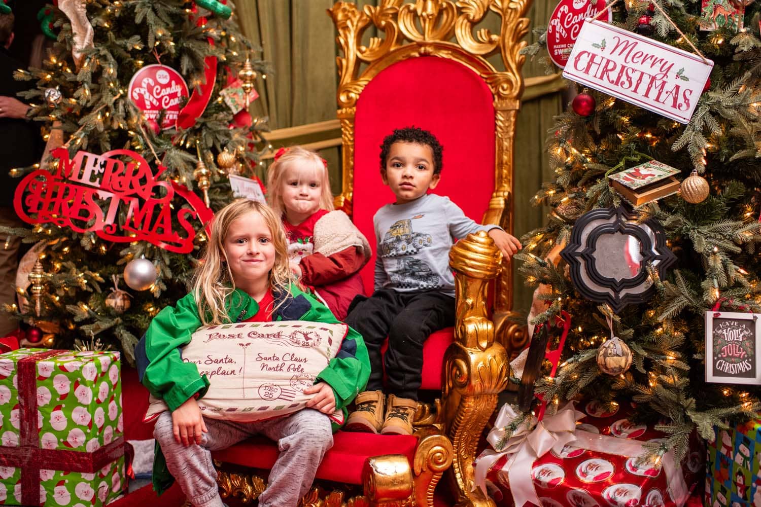 A group of children sitting in Santa's chair in a hotel lobby