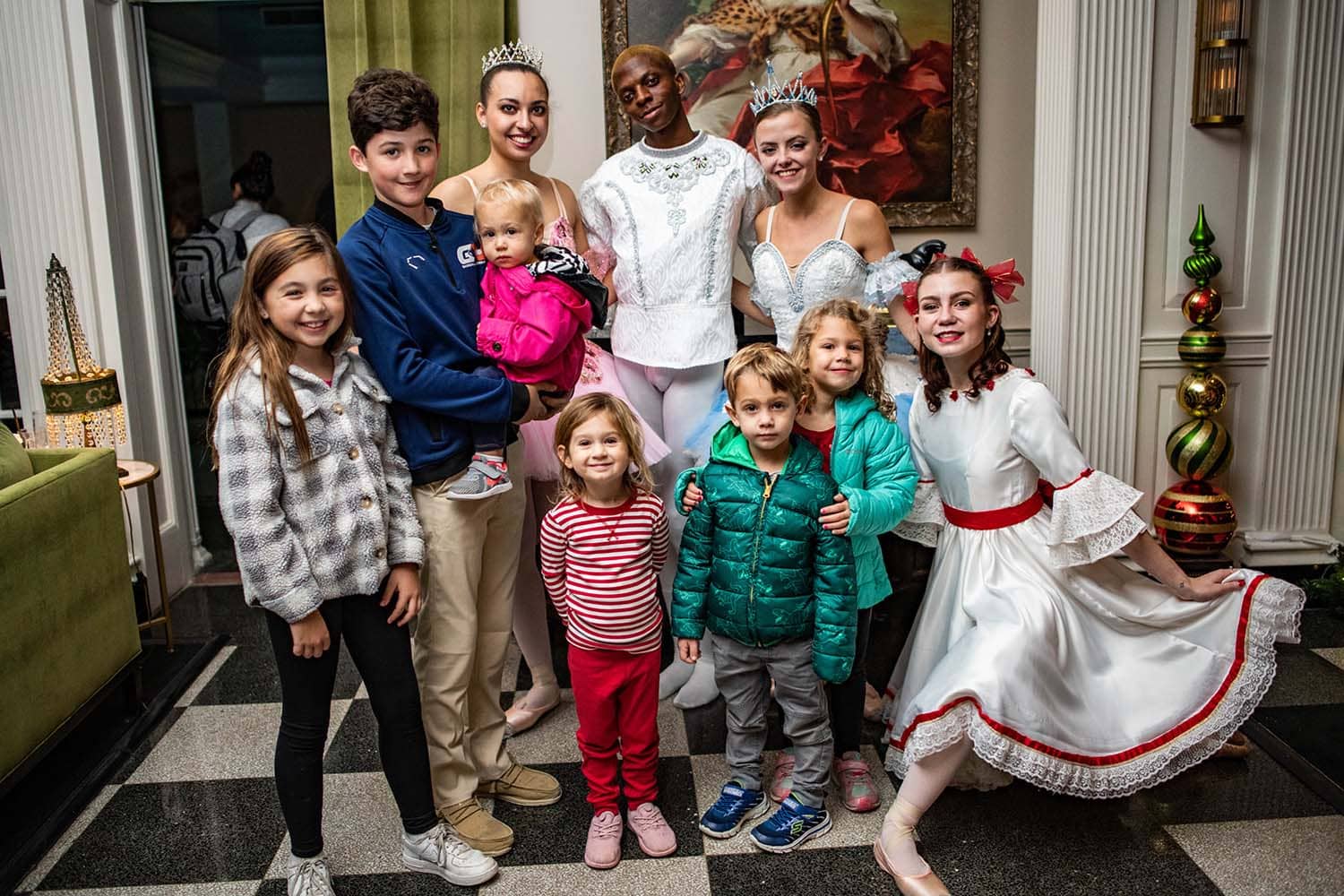 Children posing for a photo with ballerina dancers at an event