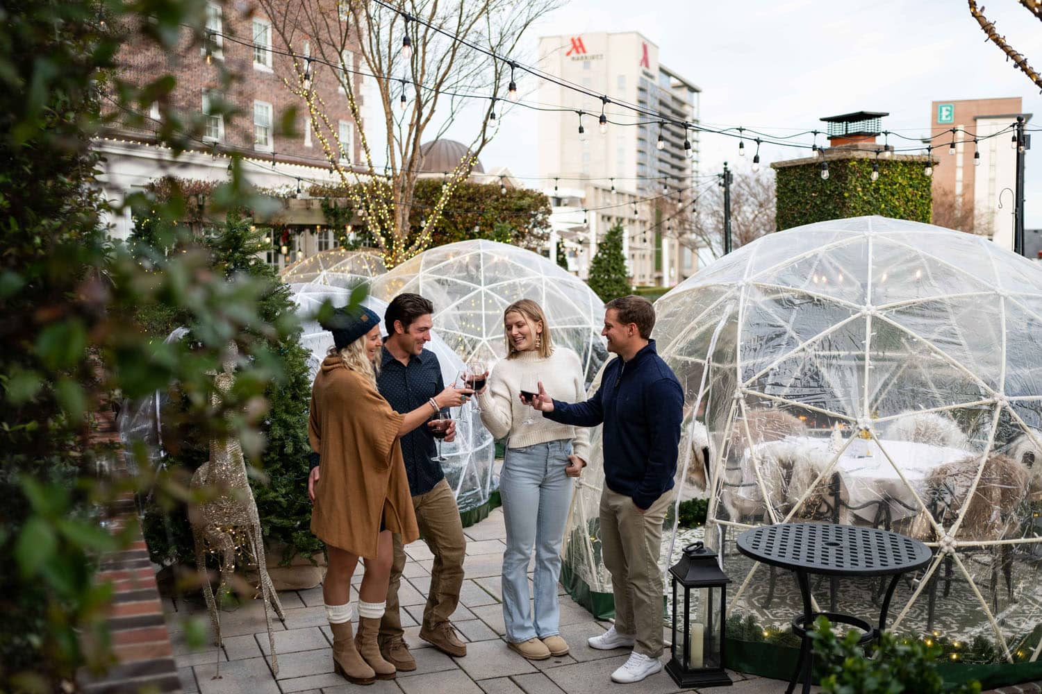 Guests standing outside of a heated igloo at Becca Restaurant & Garden