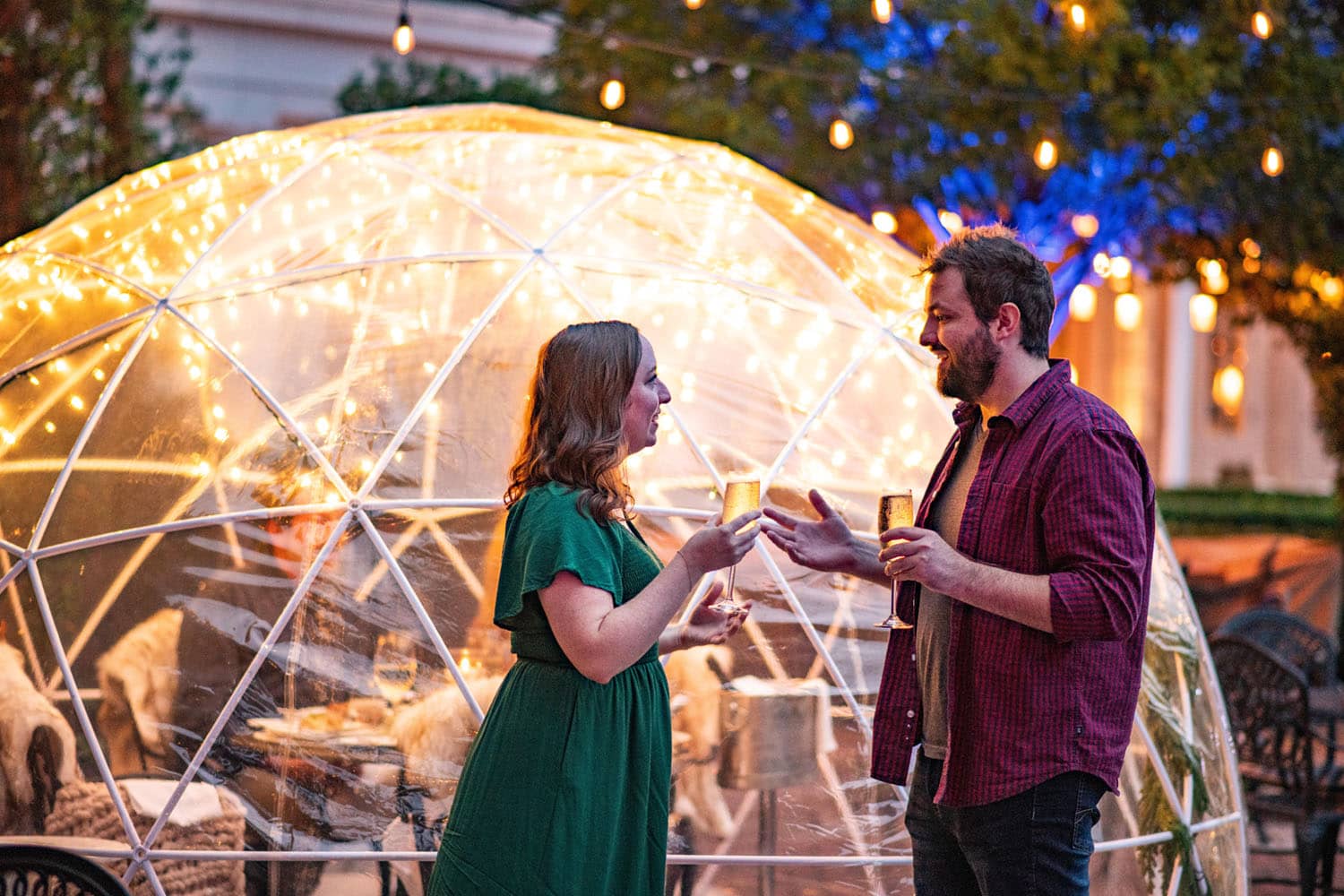 A couple sharing a moment outside an outdoor igloo at Becca Restaurant & Garden