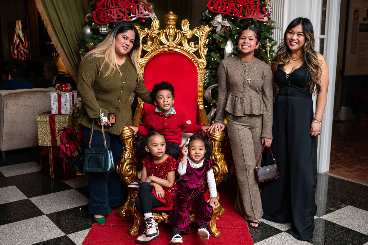 A family posing for a photo in Santa's chair at The Historic Cavalier Hotel