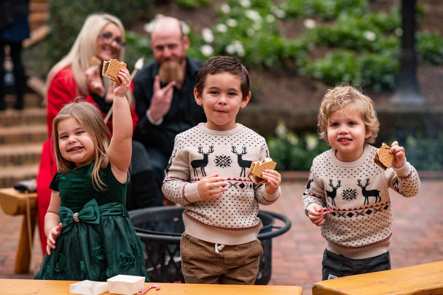 A group of children in holiday sweaters eating s'mores