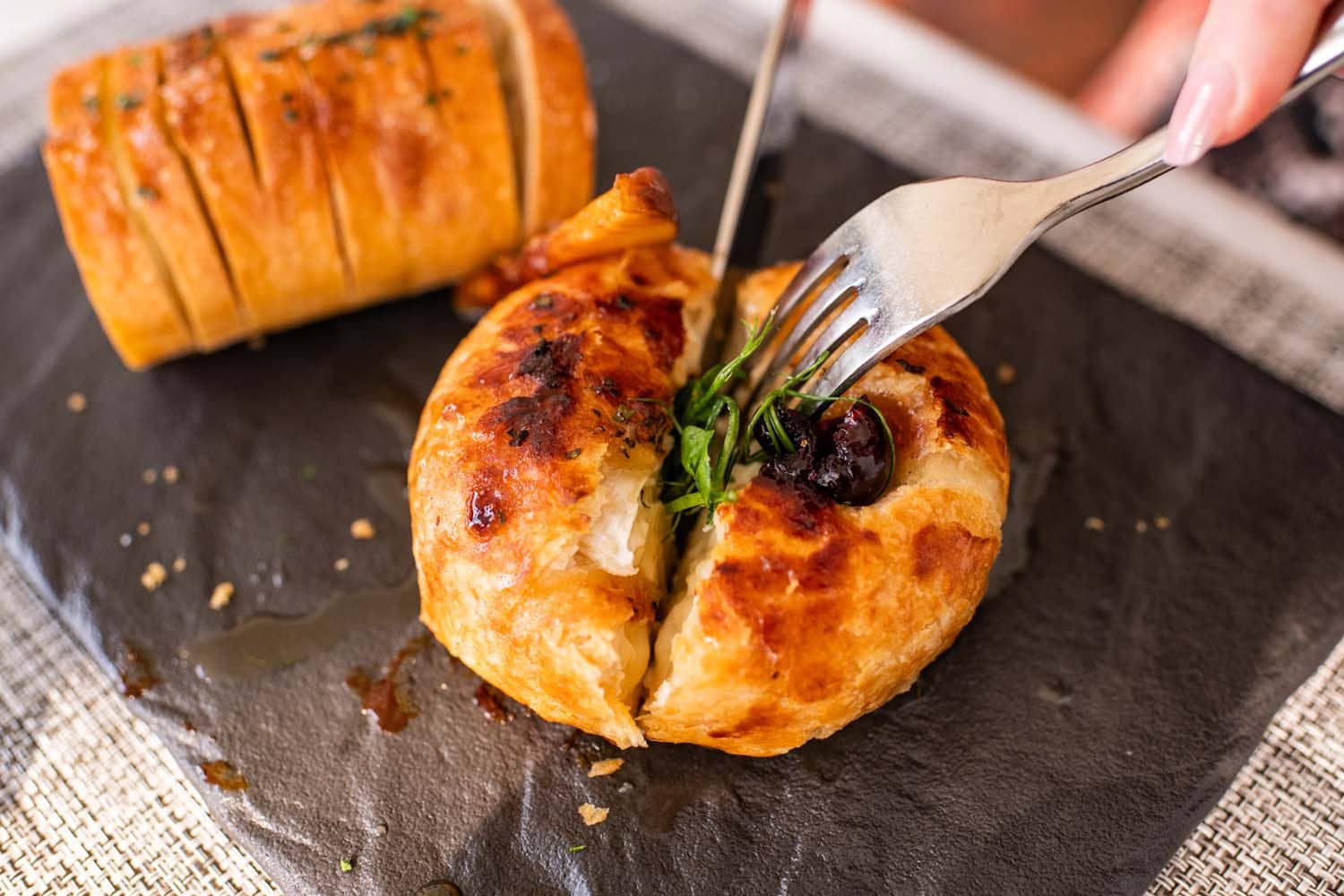 A fork and knife cutting homemade bread at Becca Restaurant & Garden