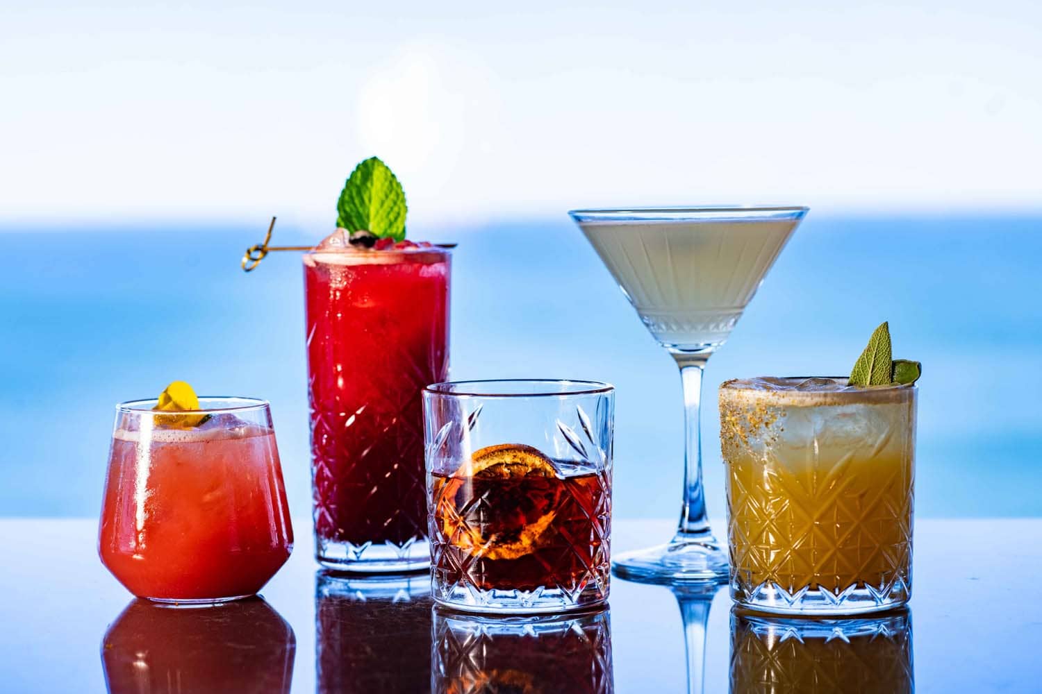 A variety of cocktail drinks on a table inside Orion's Roof Restaurant