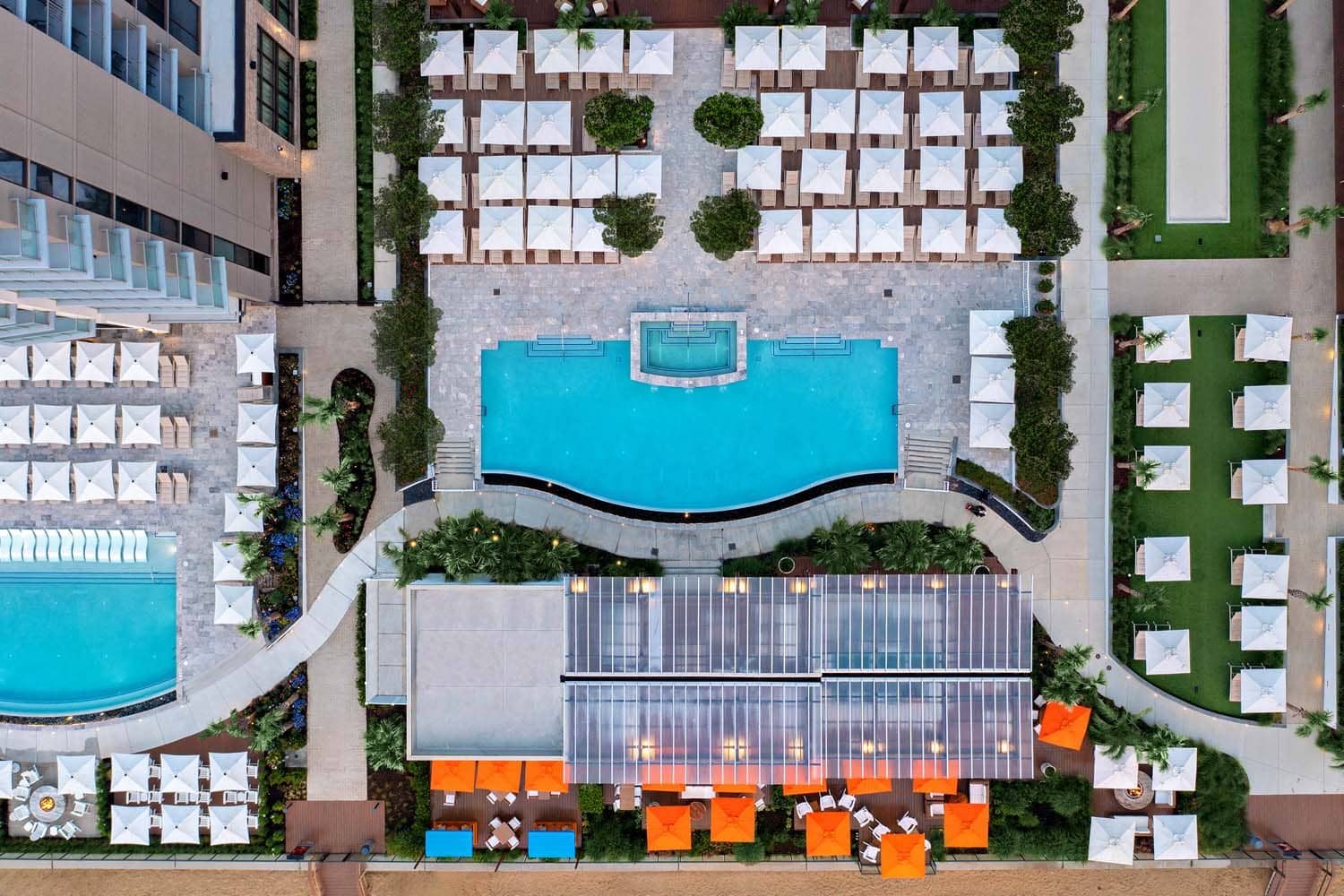An aerial birds eye view of a resort pool next to a beach