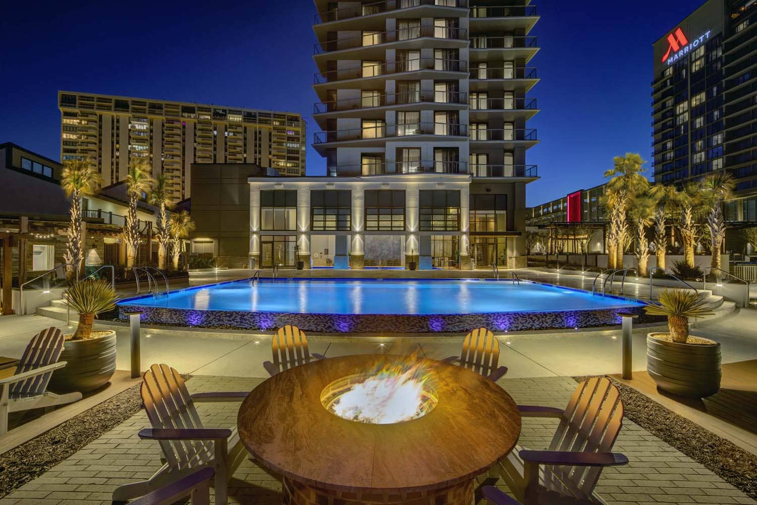 A roaring firepit alongside an outdoor resort pool at night