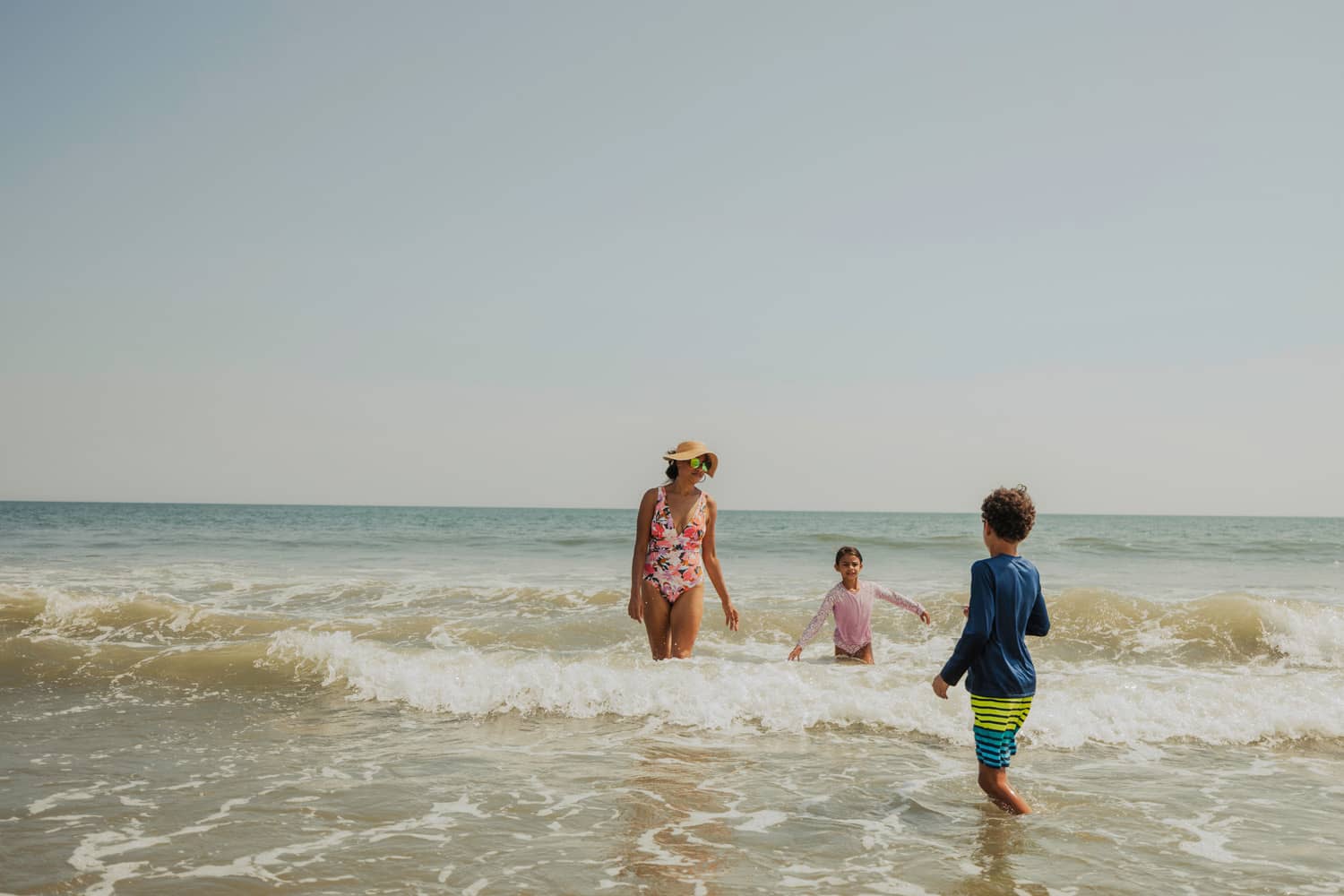 A family of three playing in the ocean waves