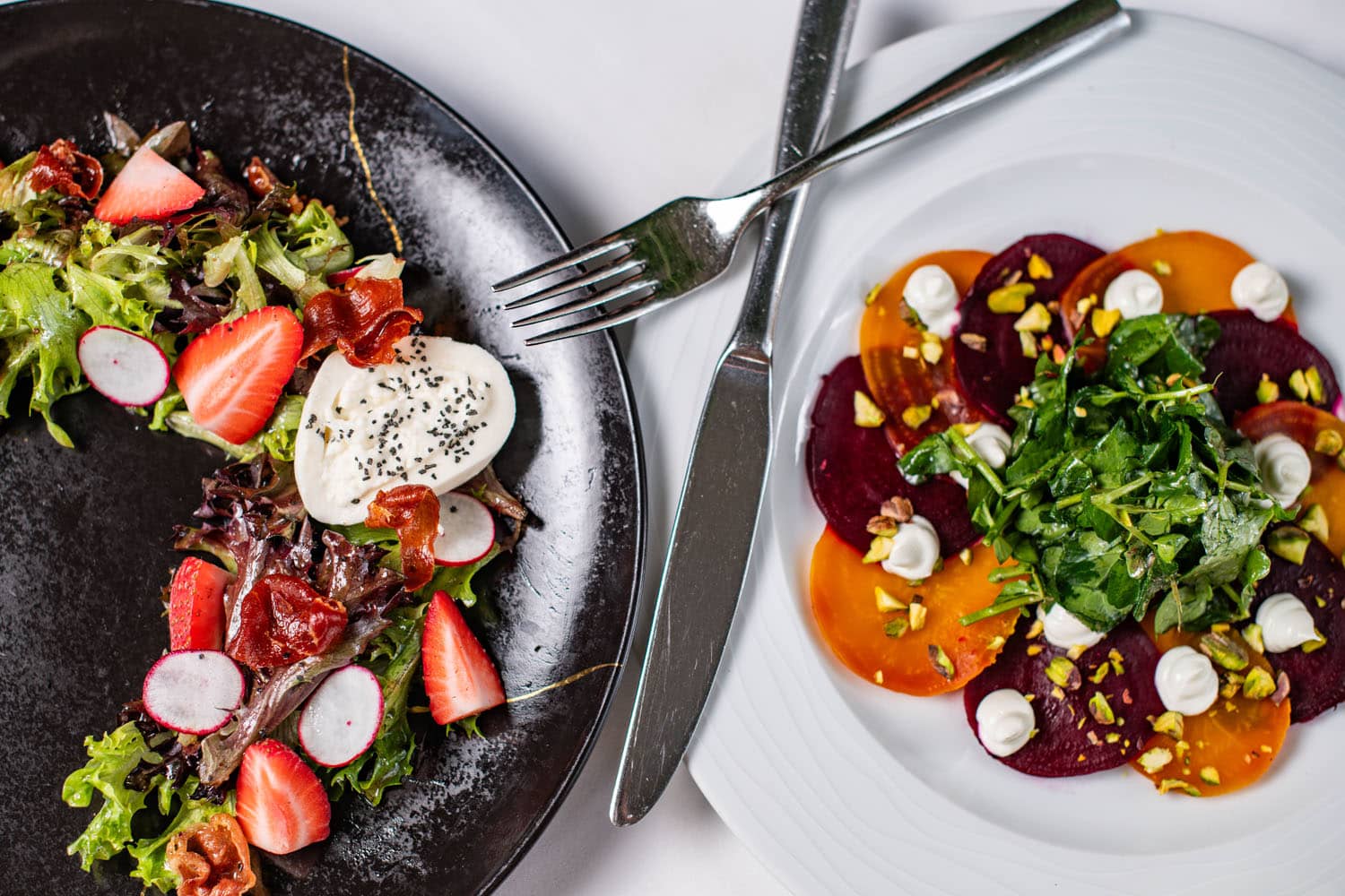 Two salads plated on a table at Becca Restaurant & Garden