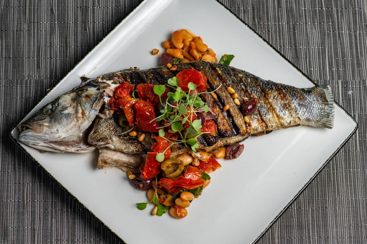 Whole roasted fish with tomatoes, olives, white beans, pine nuts, and fresh greens at Tulu Seaside Bar & Grill