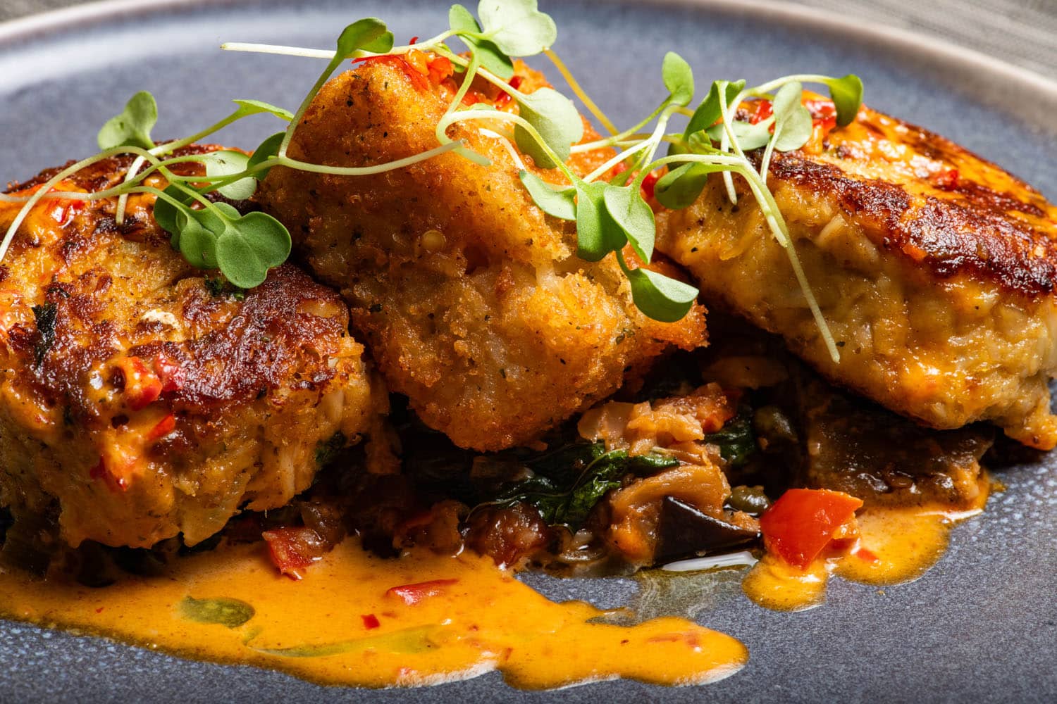 Crab cakes with crispy potatoes, vegetables, and creamy sauce at Tulu Seaside Bar & Grill